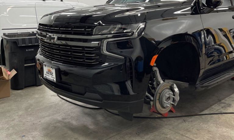 Custom Chevrolet Suburban with wheels removed for a professional ceramic coating application to ensure top-notch protection.