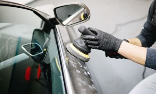 Detailer using buffer to polish paint