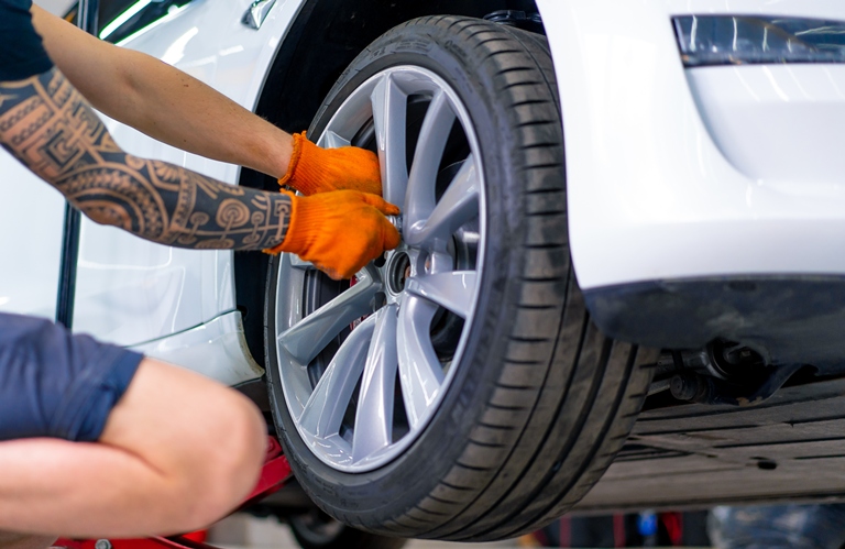 Professional auto detailer carefully removing a wheel from the car to begin the ceramic coating process.